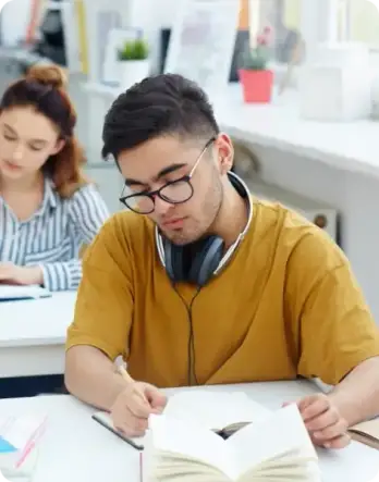 Boy writing in book with glasses and headphones